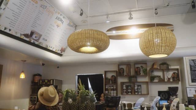 Interior shot of Aroma Caffe with bamboo chandeliers and hawaiian sculptures and motifs on wooden shelves.